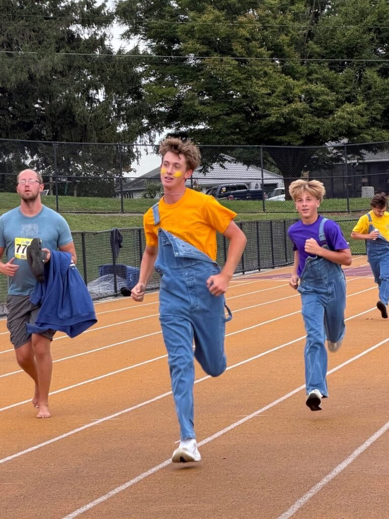 Homecoming 5K runners in overalls making their way around the track.