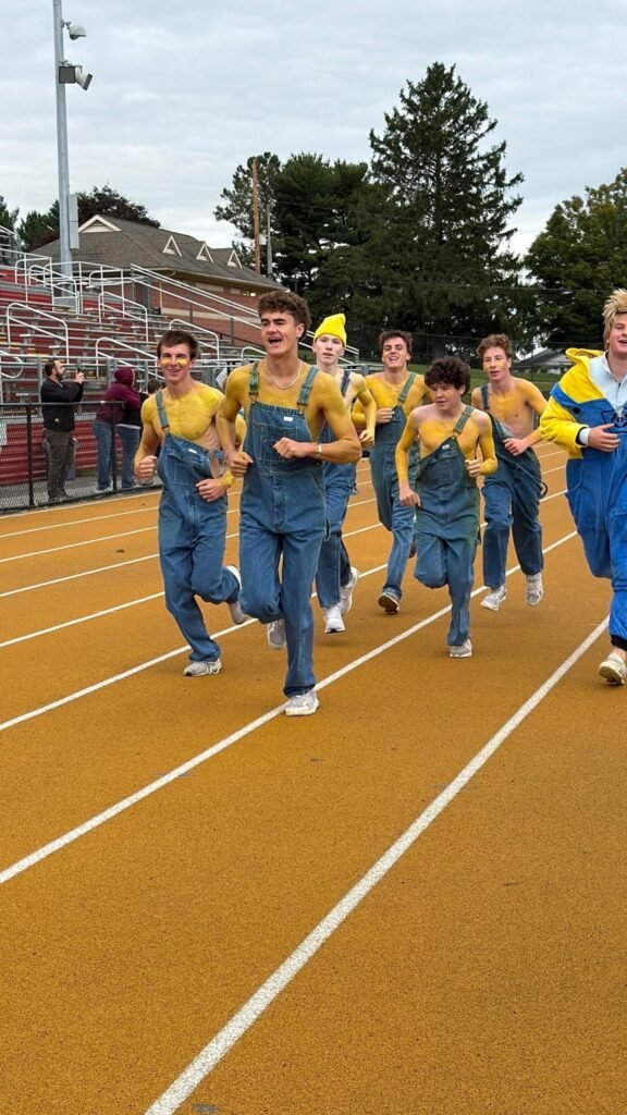 Homecoming 5K participants in Minion-inspired outfits running together on the school track.